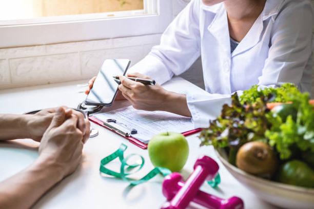 Nutritionist giving consultation to patient with healthy fruit and vegetables