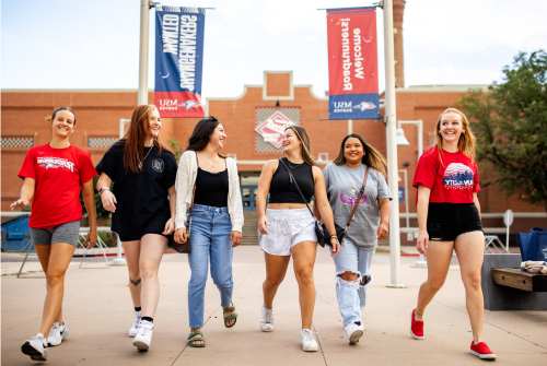 Six people walk toward the camera in with the Tivoli Student Union and MSU Denver banners in the background.