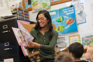 Photograph of Idalee Nunez reading a book to a group of young children in a classroom.